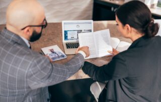 Blad man and woman looking at a pamphlet, with a laptop open behind it
